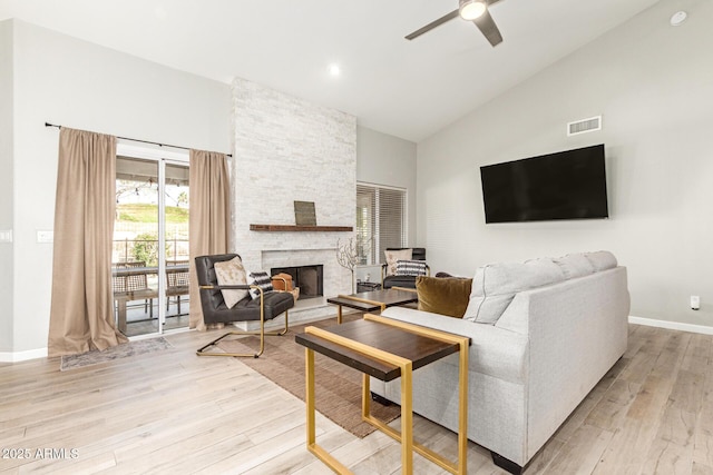 living room featuring ceiling fan, high vaulted ceiling, a fireplace, and light wood-type flooring