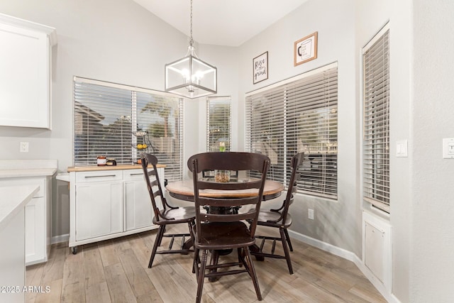 dining space with lofted ceiling, light hardwood / wood-style floors, and a chandelier