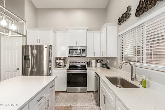 kitchen featuring sink, stainless steel appliances, hanging light fixtures, and white cabinets