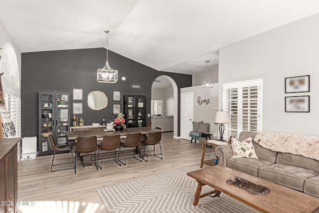 living room featuring lofted ceiling, an inviting chandelier, and light hardwood / wood-style floors