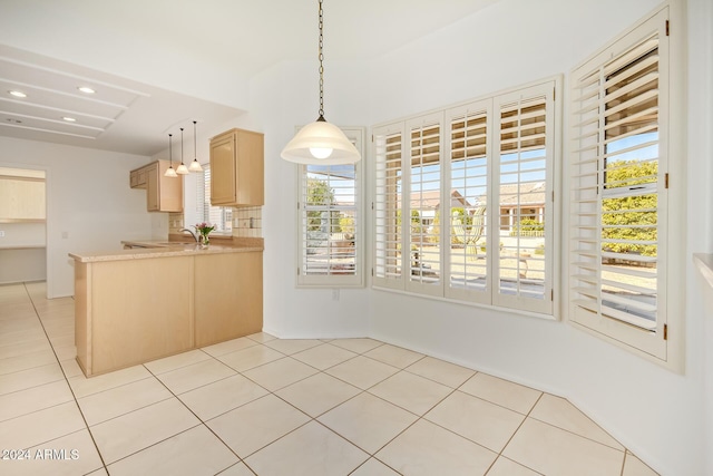 kitchen featuring kitchen peninsula, sink, light brown cabinets, hanging light fixtures, and light tile patterned flooring