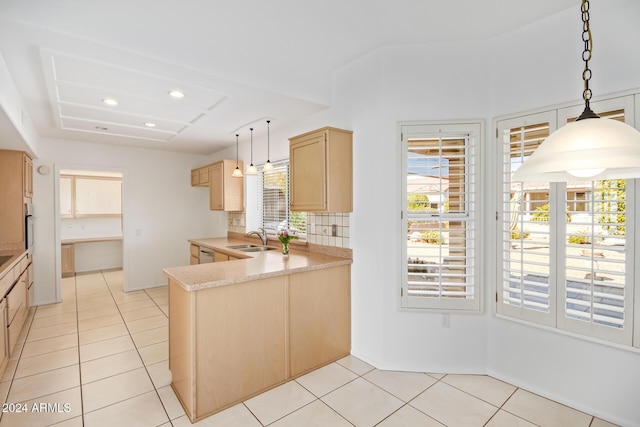 kitchen with kitchen peninsula, light brown cabinetry, decorative light fixtures, and sink