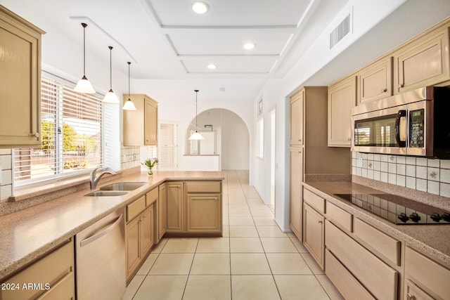 kitchen featuring appliances with stainless steel finishes, backsplash, sink, light brown cabinets, and hanging light fixtures