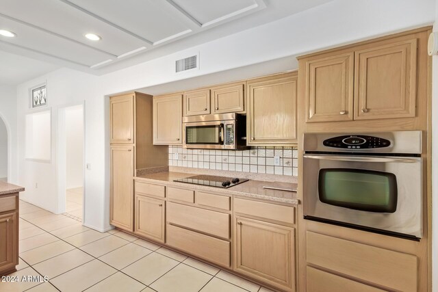 kitchen with backsplash, light brown cabinets, light tile patterned floors, and appliances with stainless steel finishes