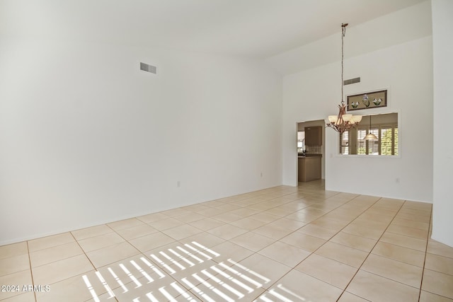 empty room featuring light tile patterned flooring, high vaulted ceiling, and an inviting chandelier