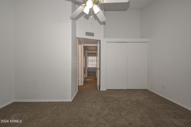 unfurnished bedroom featuring ceiling fan, a closet, and dark carpet