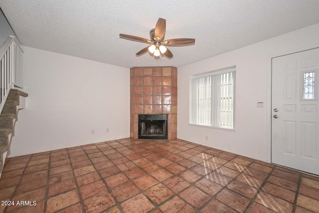 unfurnished living room featuring a textured ceiling, a tile fireplace, and ceiling fan