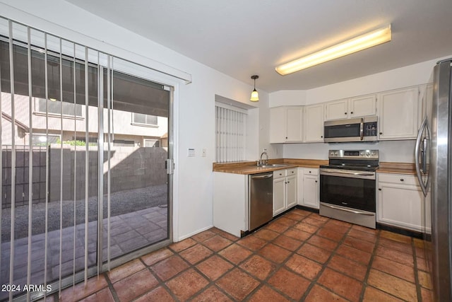 kitchen with hanging light fixtures, white cabinetry, sink, and stainless steel appliances