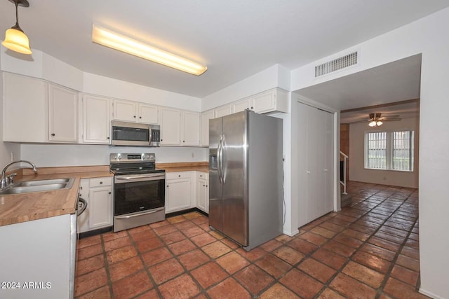 kitchen with pendant lighting, sink, white cabinetry, appliances with stainless steel finishes, and ceiling fan