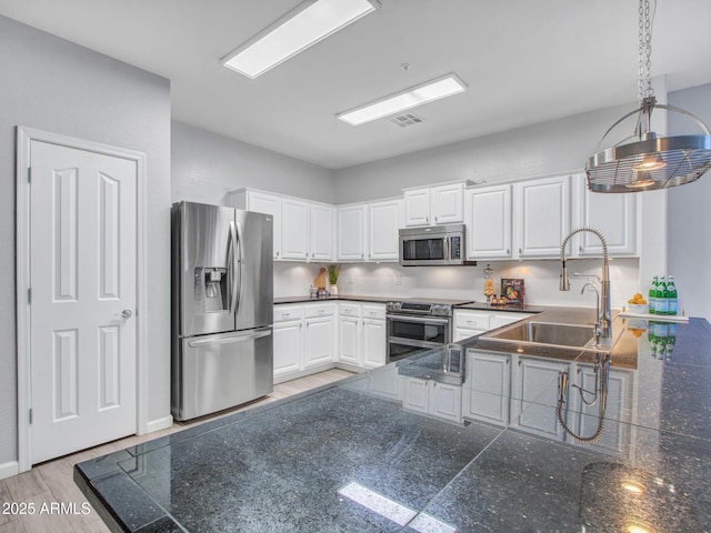 kitchen featuring pendant lighting, sink, white cabinetry, stainless steel appliances, and kitchen peninsula