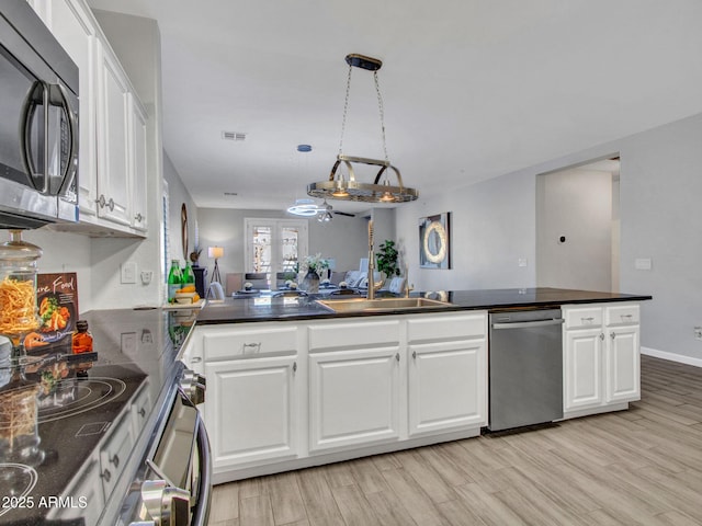 kitchen with appliances with stainless steel finishes, kitchen peninsula, sink, and white cabinets