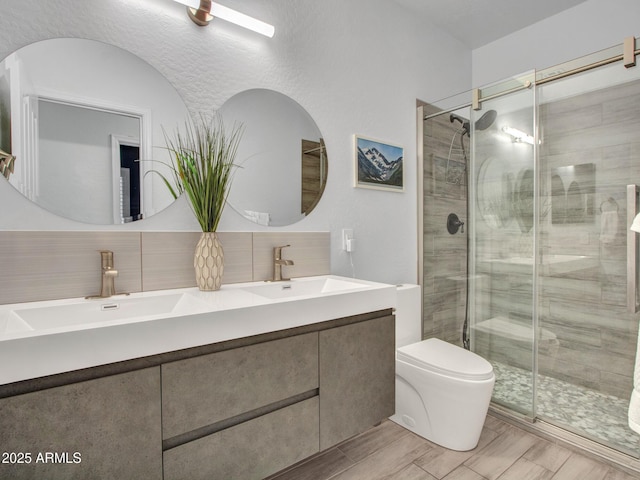 bathroom featuring tasteful backsplash, toilet, vanity, and a shower with shower door