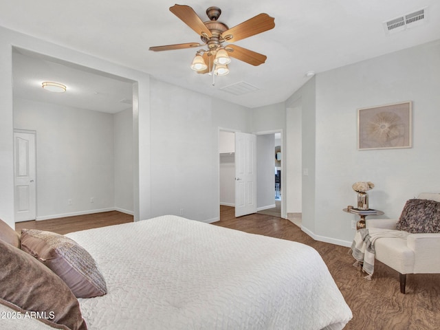 bedroom with dark hardwood / wood-style flooring, a spacious closet, and ceiling fan