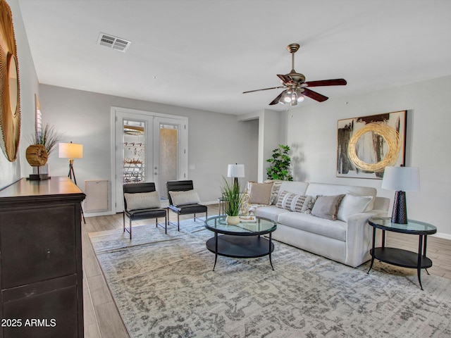 living room with ceiling fan, light wood-type flooring, and french doors