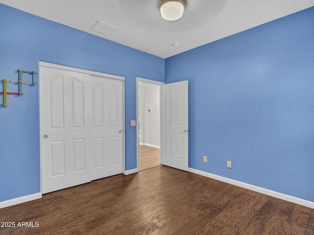 unfurnished bedroom with dark wood-type flooring and a closet