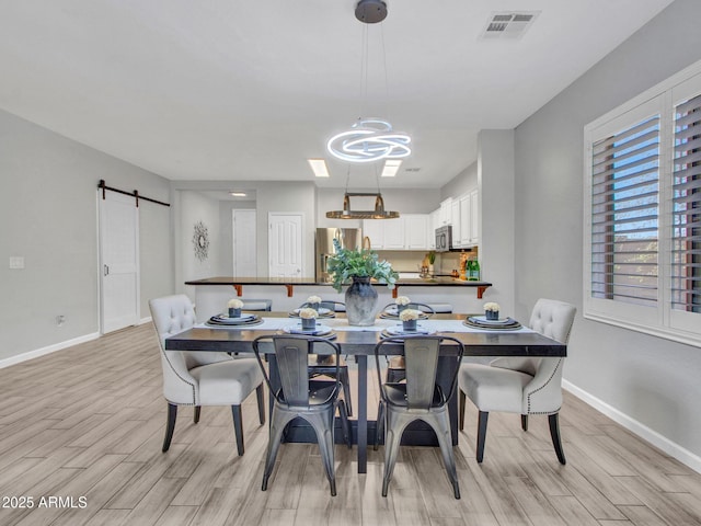 dining area featuring a barn door and light hardwood / wood-style flooring