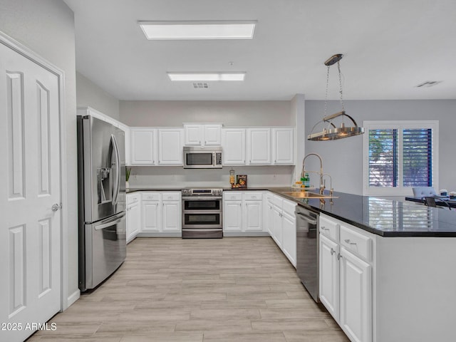 kitchen featuring decorative light fixtures, sink, white cabinets, kitchen peninsula, and stainless steel appliances