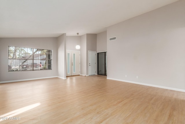 unfurnished living room featuring vaulted ceiling and light hardwood / wood-style flooring