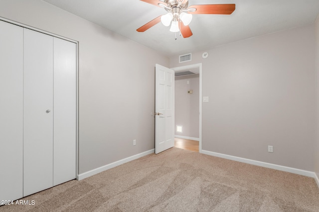 unfurnished bedroom featuring light carpet, a closet, and ceiling fan