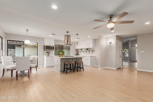 kitchen with appliances with stainless steel finishes, white cabinetry, light wood-type flooring, and pendant lighting