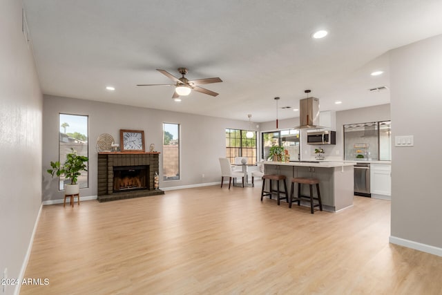 living room with light hardwood / wood-style flooring, a fireplace, and ceiling fan