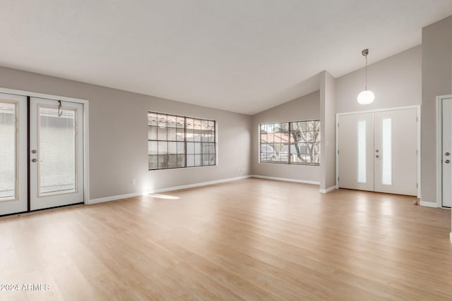 entrance foyer with french doors, high vaulted ceiling, and light hardwood / wood-style floors