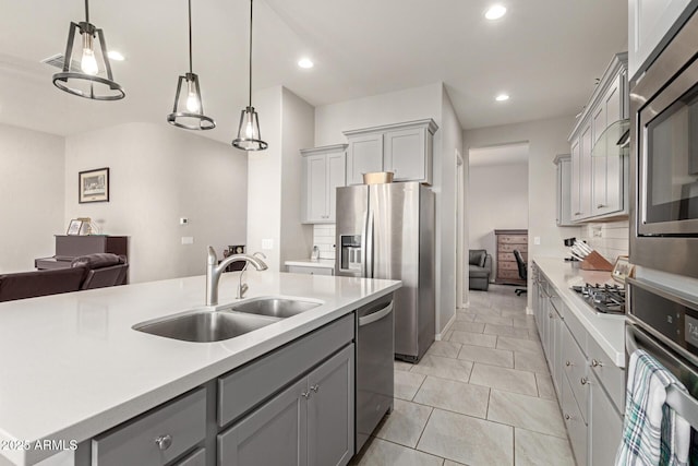 kitchen with sink, gray cabinetry, hanging light fixtures, stainless steel appliances, and decorative backsplash