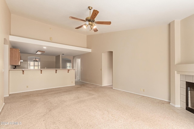 unfurnished living room featuring light carpet, ceiling fan, and a tiled fireplace