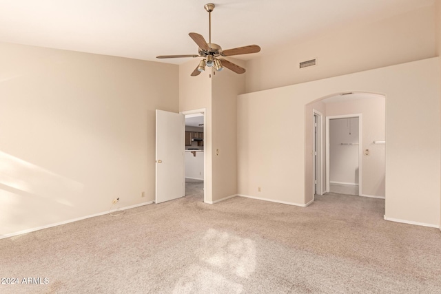 interior space featuring ceiling fan, light colored carpet, and a high ceiling