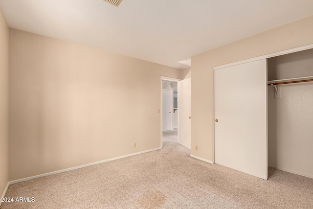 unfurnished bedroom with light carpet and a closet