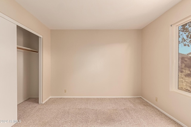 unfurnished bedroom featuring light colored carpet and a closet