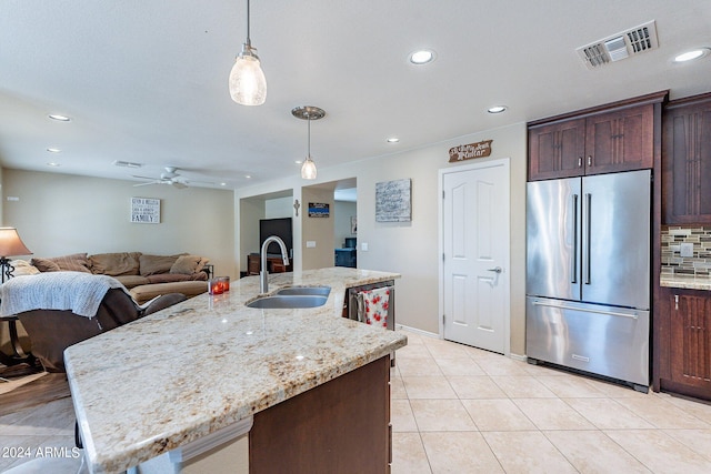 kitchen featuring appliances with stainless steel finishes, sink, pendant lighting, and light stone counters