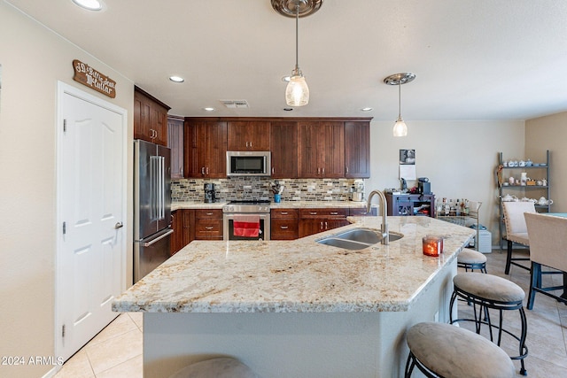 kitchen with decorative light fixtures, tasteful backsplash, sink, light tile patterned floors, and premium appliances