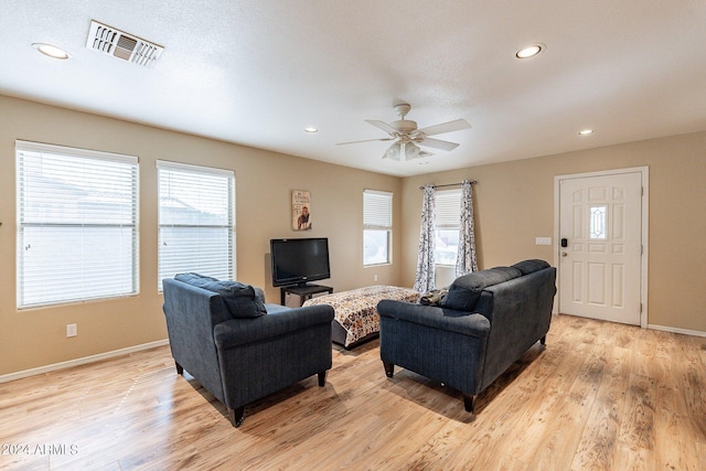 living room with ceiling fan, light wood-type flooring, and a wealth of natural light