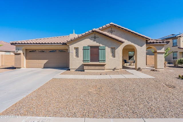 mediterranean / spanish home with a garage, driveway, a tiled roof, and stucco siding