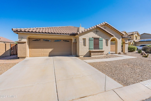 mediterranean / spanish-style home featuring a garage, concrete driveway, a tiled roof, and stucco siding