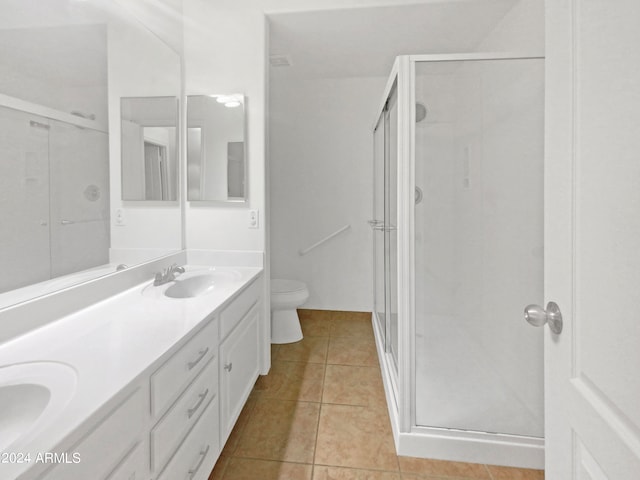 bathroom with dual vanity, tile flooring, toilet, and a shower with shower door