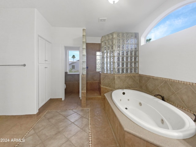 bathroom featuring tiled tub and tile floors