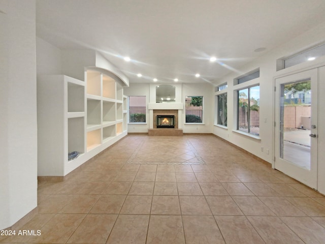 unfurnished living room featuring built in shelves, french doors, and light tile floors