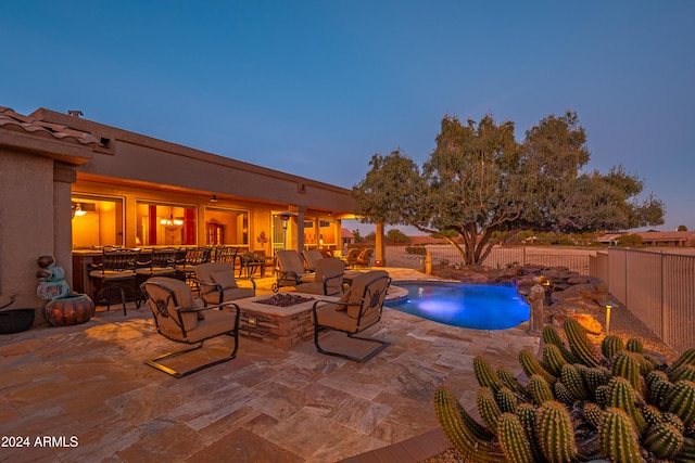 pool at dusk with a patio area and a fire pit