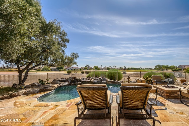 view of swimming pool with pool water feature, a patio, and a fire pit