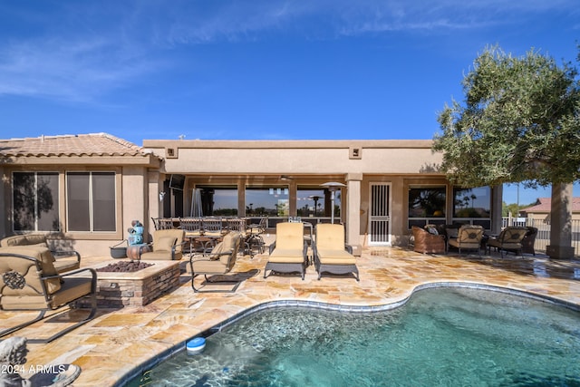 rear view of property featuring a patio and an outdoor living space with a fire pit