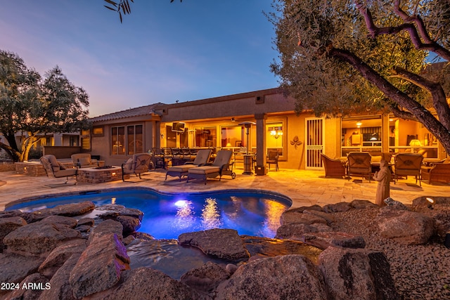 pool at dusk featuring a fire pit and a patio area