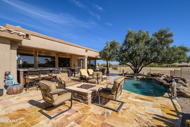 view of pool featuring pool water feature, a patio, and a fire pit