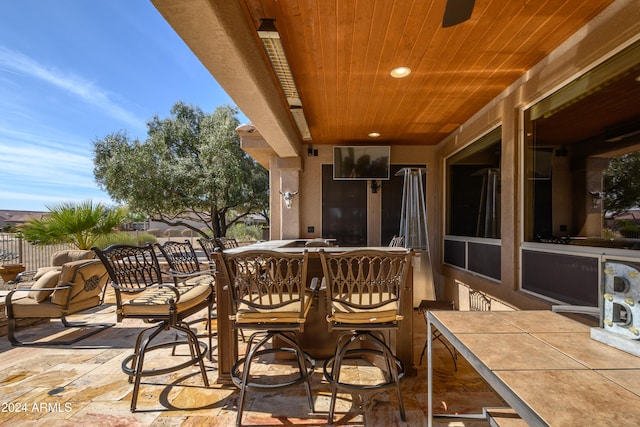 exterior space with ceiling fan, a patio area, and a bar