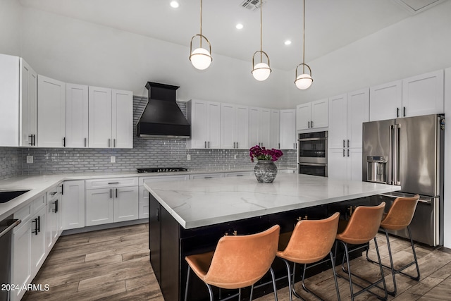 kitchen featuring a center island, premium range hood, backsplash, appliances with stainless steel finishes, and hardwood / wood-style flooring