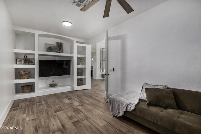 living room with hardwood / wood-style flooring, built in features, and ceiling fan