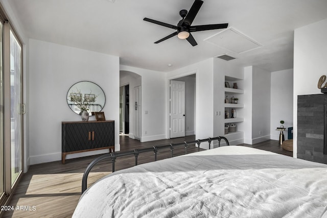 bedroom with dark wood-type flooring, ceiling fan, and a fireplace