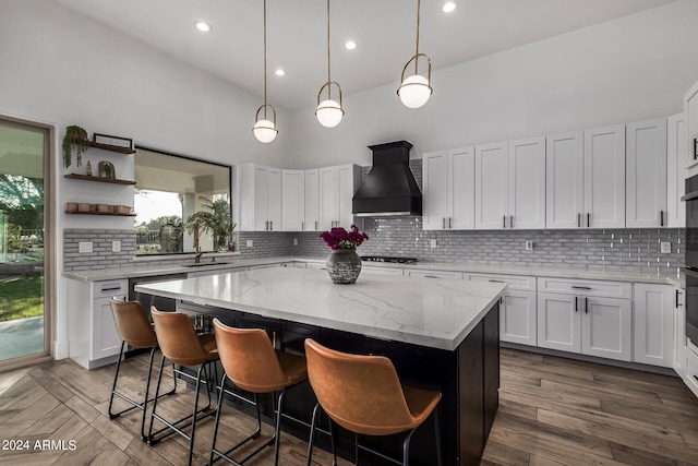 kitchen featuring white cabinets, backsplash, custom range hood, and a center island