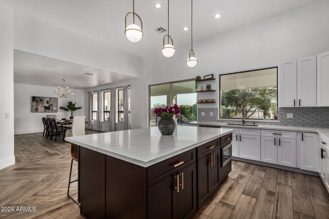 kitchen with a center island, white cabinetry, backsplash, and decorative light fixtures